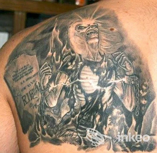 Grindato tatuaggio realistico su spalla/dorso mostrante una figura spettrale o demoniaca, tonalità nere e grigie, intricato disegno anatomico su pelle reale.