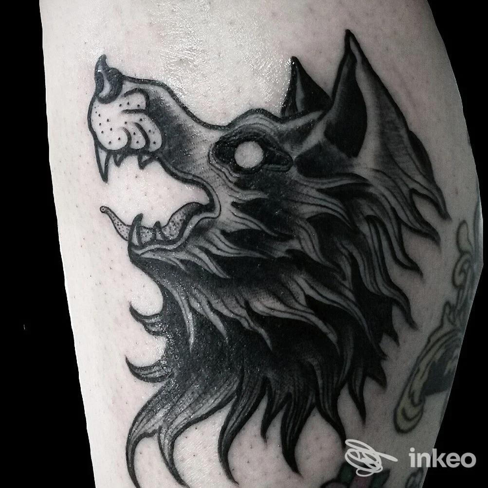 Dettaglio di un tatuaggio realistico di un lupo su pelle, visibile sul braccio con linee nette e sfumature scure; studio Jolly Roger Tattoo Studio, Montesilvano.