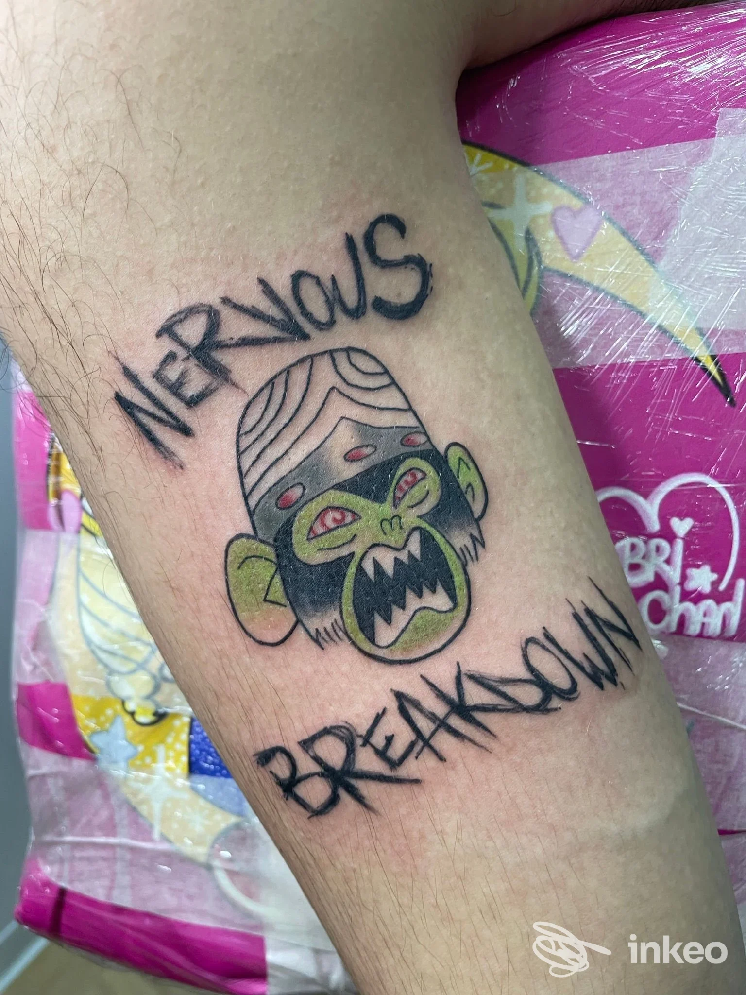 Tatuaggio sul braccio raffigurante una testa di scimmia urlante con le parole Nervous Breakdown intorno, realizzato sulla pelle.