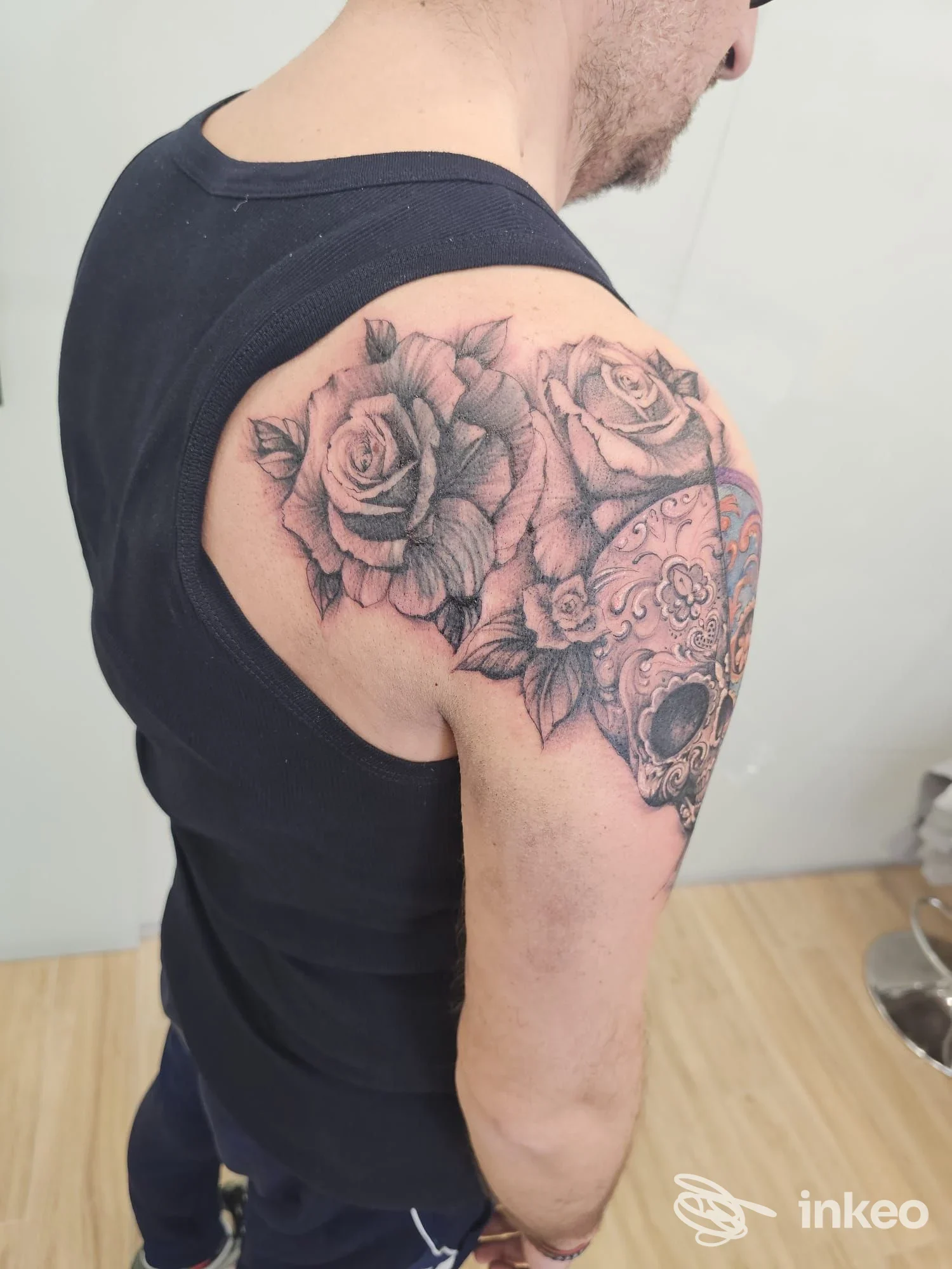 Tattoo visibile sul braccio di un uomo: motivo di rose in stile realistico in bianco e nero sulla spalla e parte superiore del braccio.