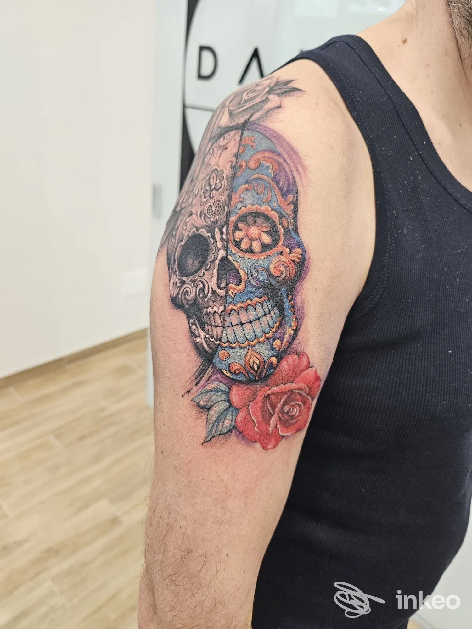 Tattoo a tema Day of the Dead su braccio sinistro: skull decorate con rose rosse e sfumature colorate realizzato sulla pelle, studio Dana Art Tattoo a Pescara.