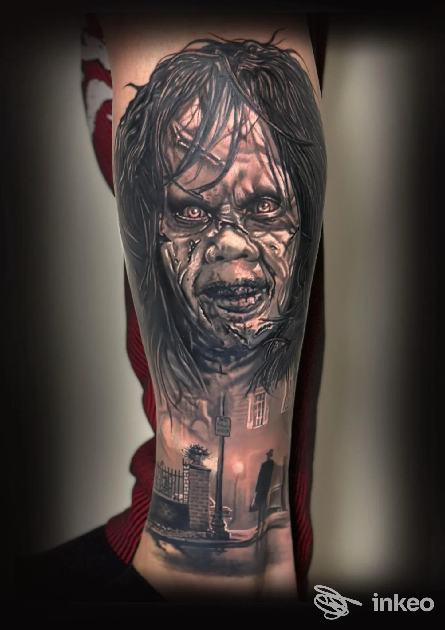 Fotografia ravvicinata di un braccio sinistro con un tatuaggio realistico: volto di zombie e scena urbana in bianco e nero.