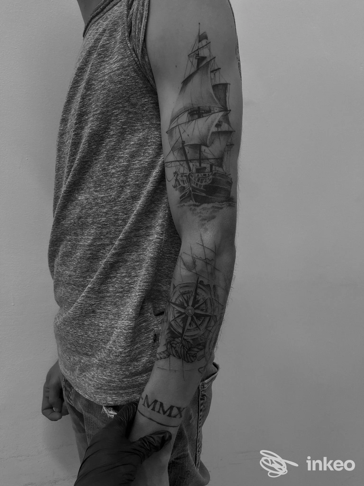 Braccio di una persona con tatuaggio realistico di una nave a vele, versione in bianco e nero.