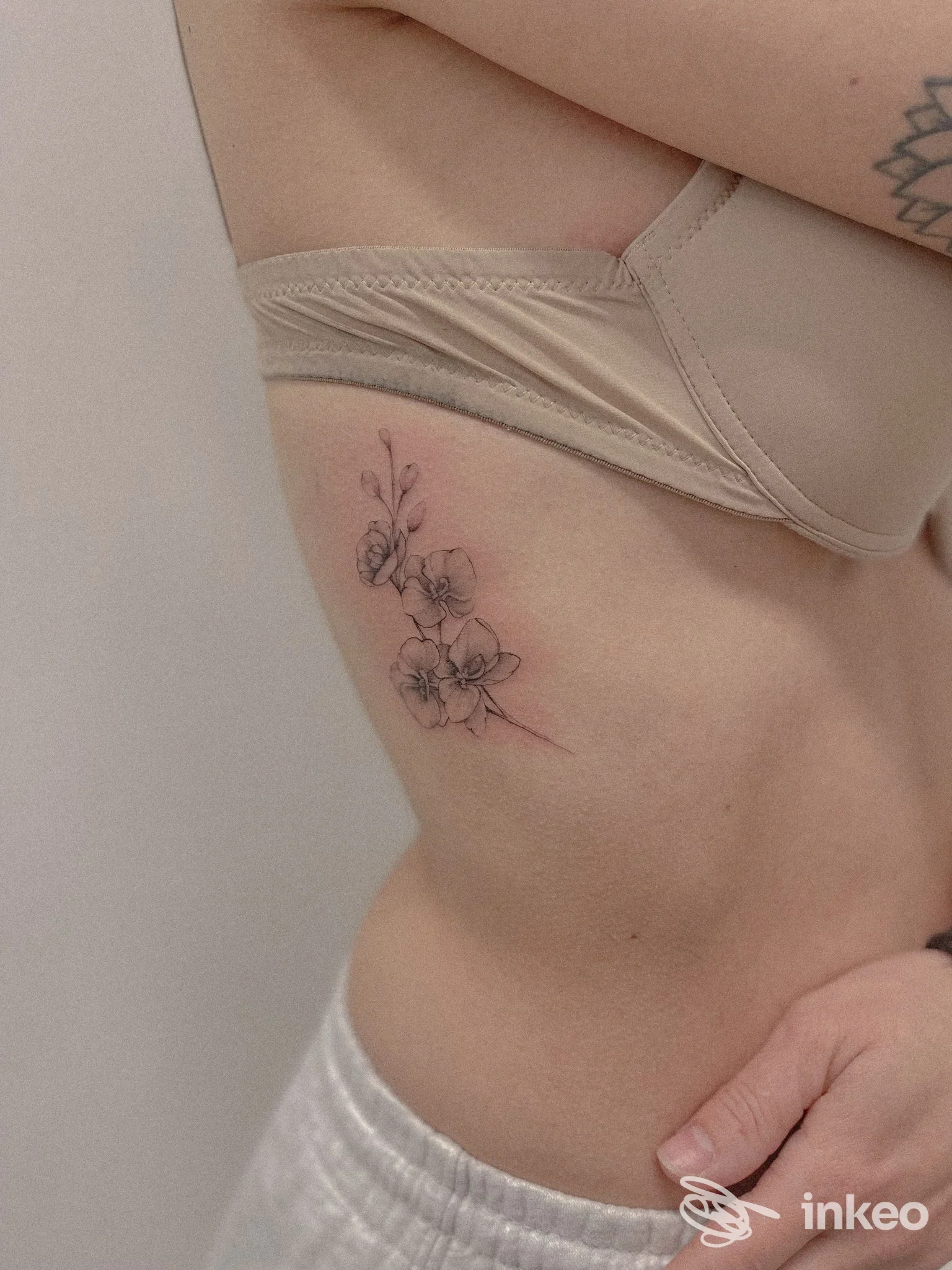 Particolare laterale del fianco con un piccolo tatuaggio floreale su pelle chiara, eseguito da Lady Sofia Tattoo a Manoppello Scalo.