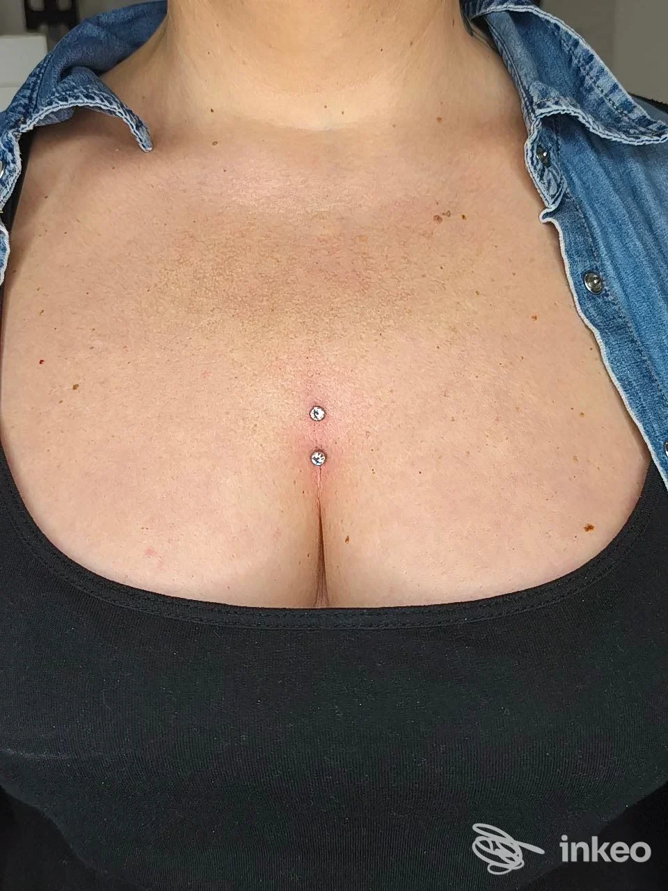 Due piercing dermici verticali al centro del torace, visibili sulla pelle, indossati senza alcuna sovrascrittura. foto di studio non ritrae il volto.