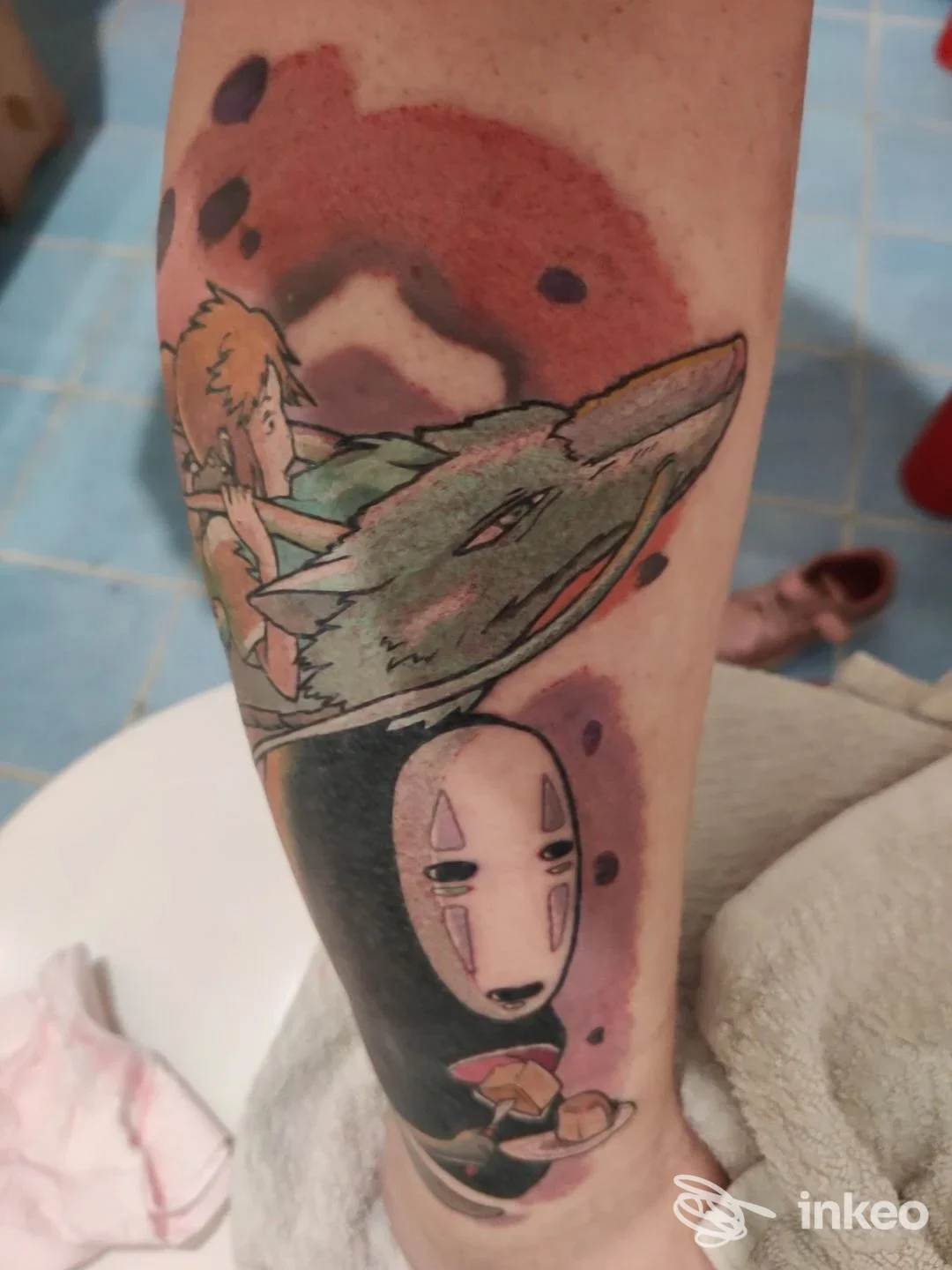 Tatuaggio visibile sull'avambraccio raffigurante creature in stile anime con colori vividi e linee nette, parte di un braccio, nessun volto intero visibile.