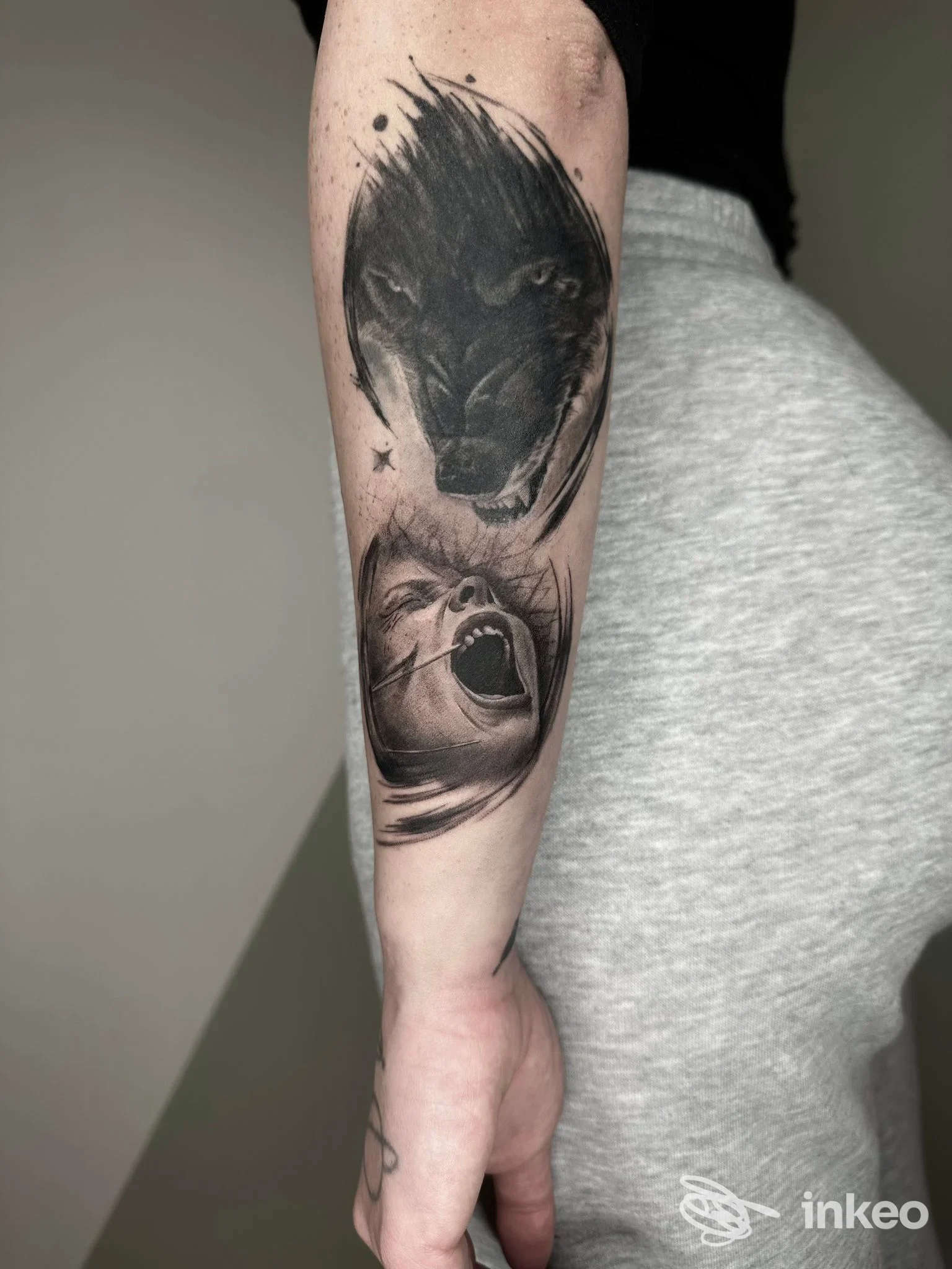 Tatuaggio su braccio raffigurante una testa di lupo nera e un volto urlante, realizzato dallo studio Minimal a L'Aquila.