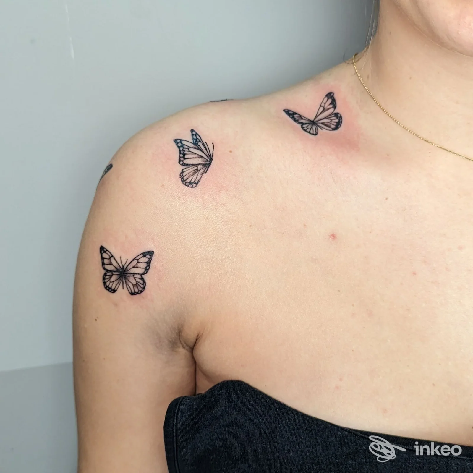 Tat tatouaggi di farfalle realizzati sulla spalla e sul décolleté di una persona, inchiostrati in nero su pelle chiara.
