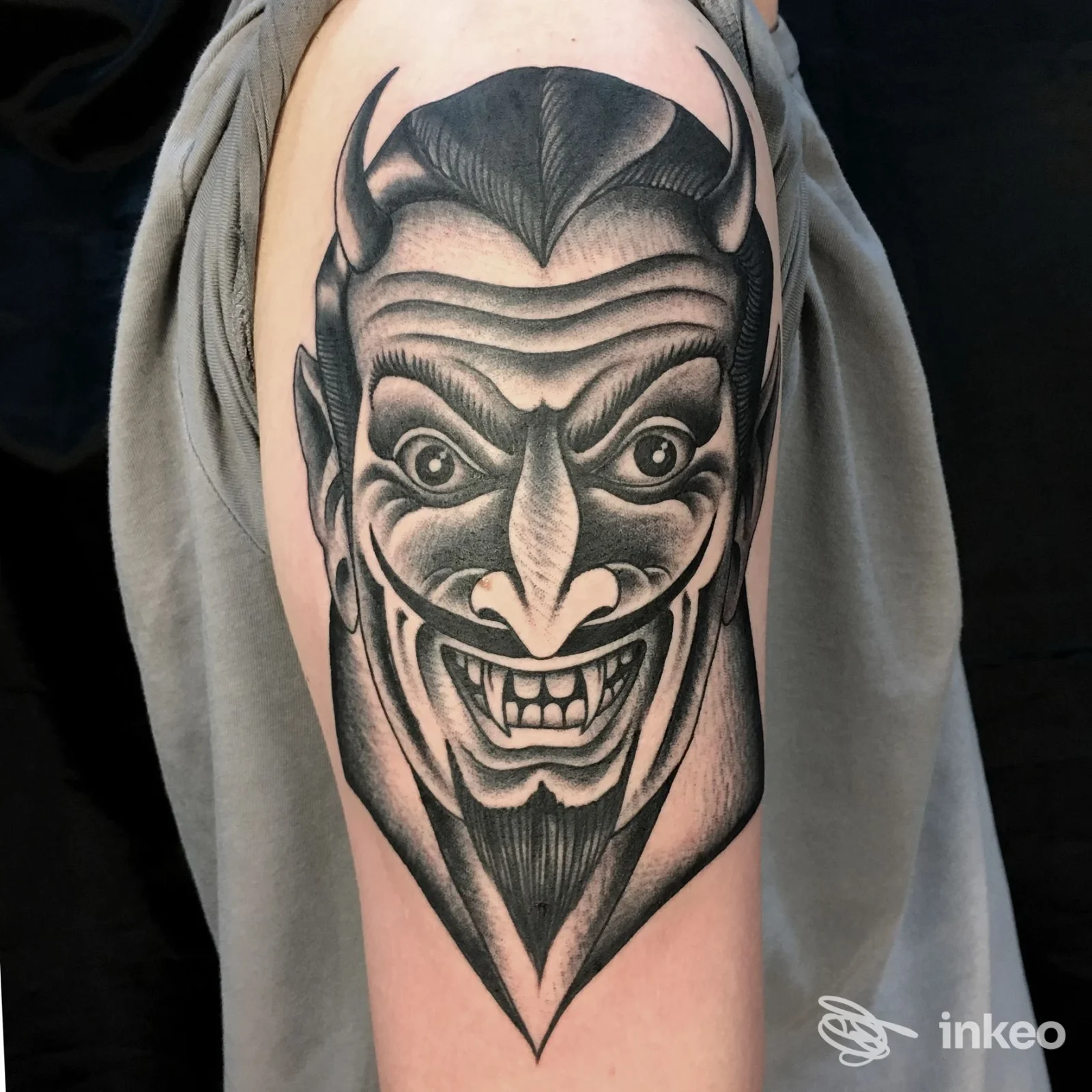 Tattoo visibile sul braccio di una persona: tratto nero/grigio in stile fumettoso, figura demoniaca con contorni netti e sfumature.
