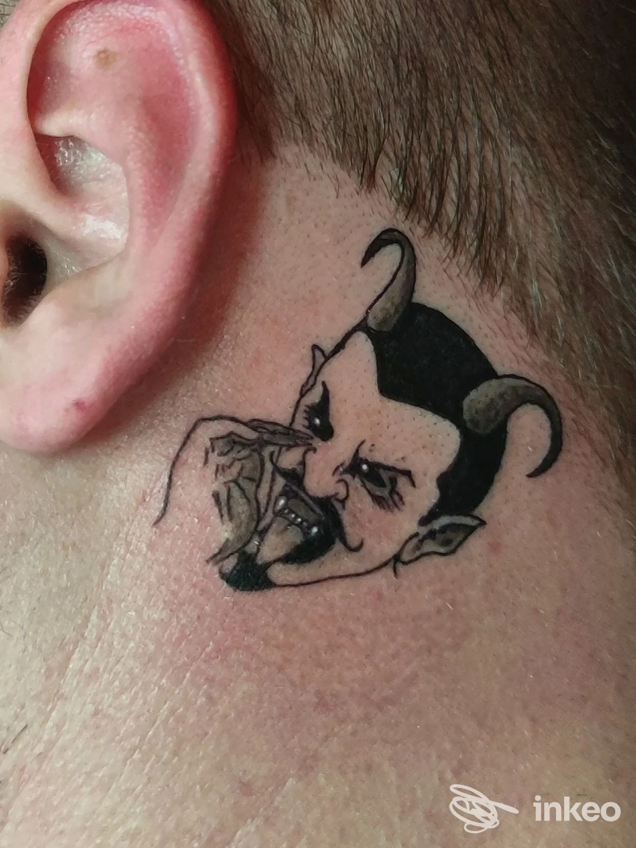 Tatuaggio su collo raffigurante un diavolo con corna, disegnato in stile nero e grigio, visibile sulla pelle reale senza presenza di volto umano completo.