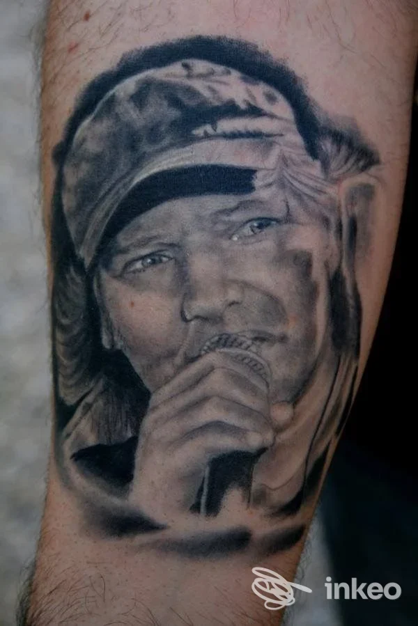 Ritratto realistico di una persona che canta, tatuaggio su avambraccio, tonalità in bianco e nero, realizzato sulla pelle.