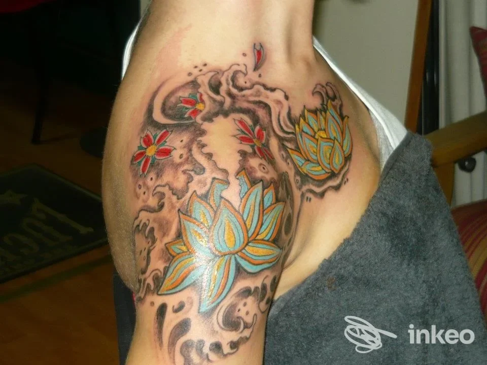Tattoo sull’avambraccio/petto visibile: motivo floreale lotus azzurro e giallo con sfumature e contorni scuri, realizzato sulla pelle in Pescara da Tattoo, Lucha y Rock’n’Roll.