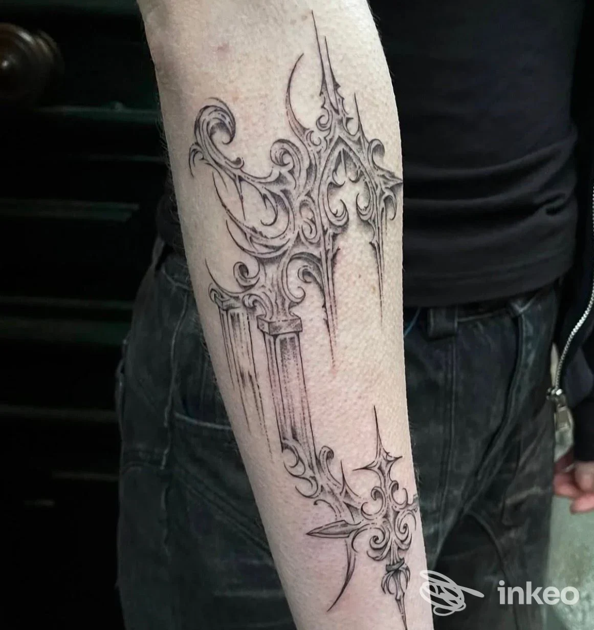 Tattoo sul braccio con motivo ornamentale in stile gotico realizzato sulla pelle, visibile su sfondo di jeans e maglietta, presso lo studio Joe Black Tattoo, Alba Adriatica.