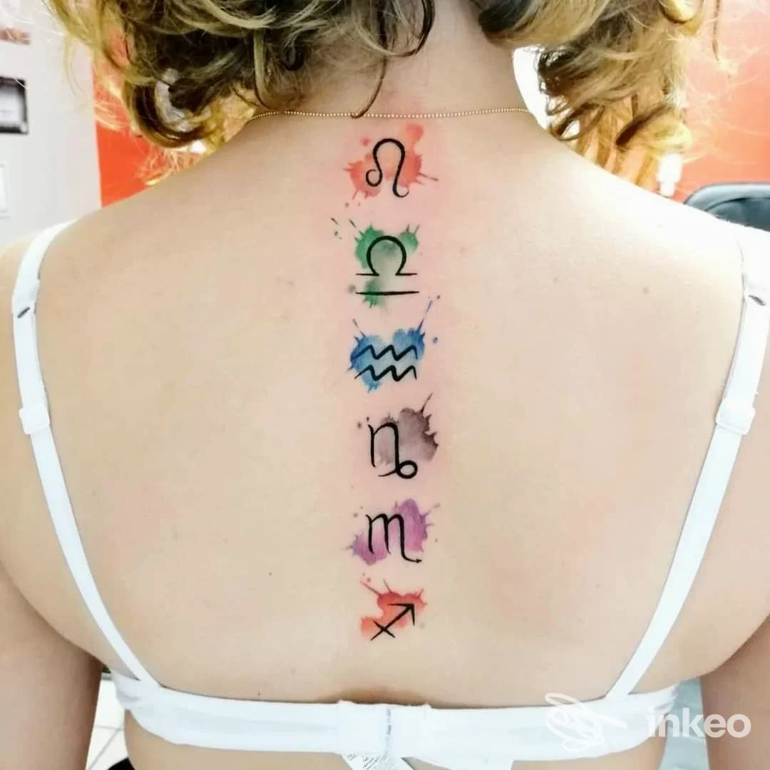 Tattoo longitudinale sulla schiena raffigurante simboli zodiacali con sfumature colorate in rosso, verde, azzurro e viola. l’immagine mostra la pelle esposta senza volto visibile.