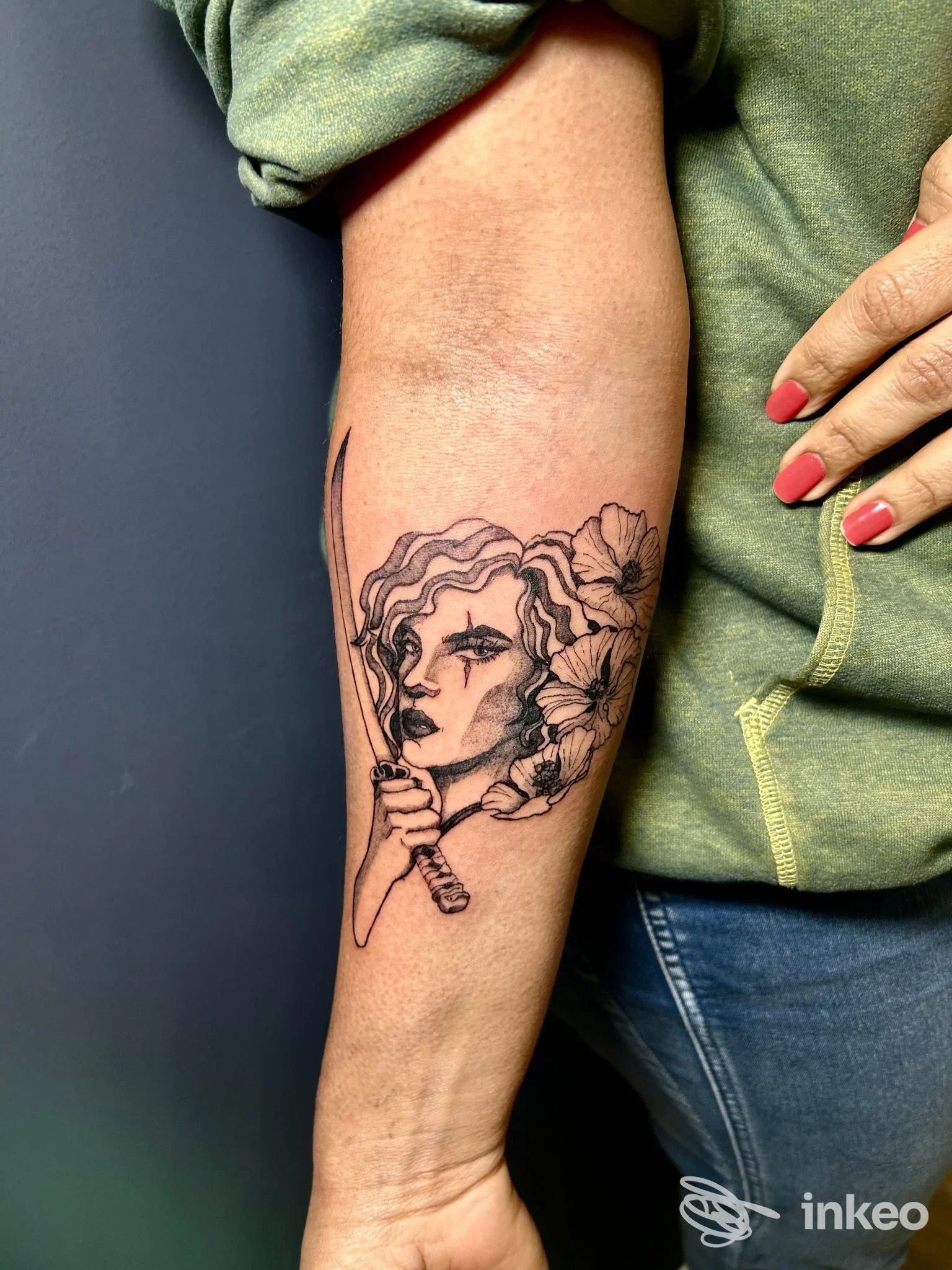 Tattoo su avambraccio raffigurante una donna tra fiori, realizzata in linea nera, visibile in primo piano sull’avambraccio di una persona. studio Splat Ink TattooShop a Vimercate.
