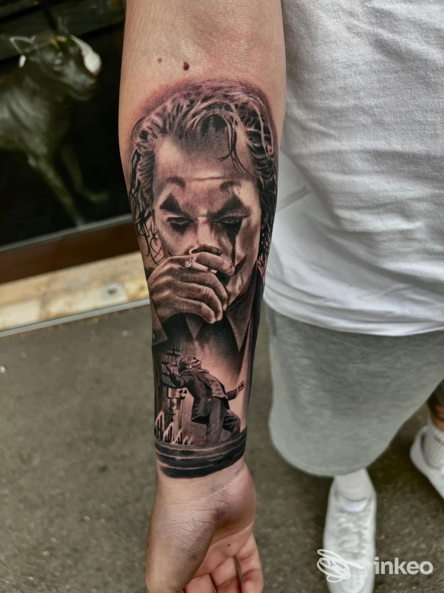 Tattoo realistico in bianco e nero sull’avambraccio: ritratto di persona con dettaglio del volto e scena urbana sul polpaccio inferiore, eseguito nello studio The Lab Tattoo a Montesilvano.