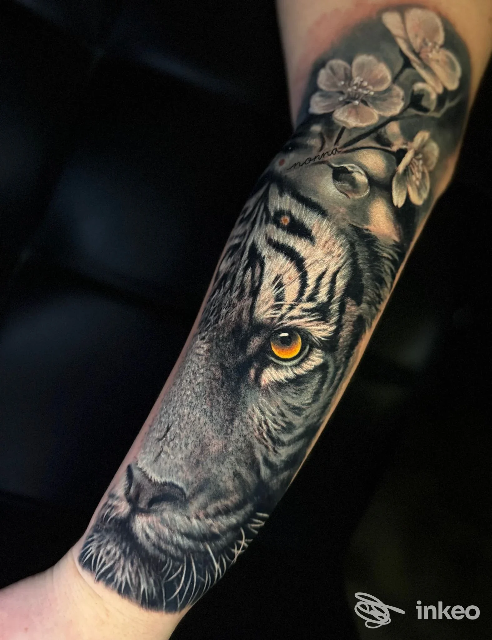 Tattoo realistico di tigre con fiori realizzato da Gabriel Andrasi Tattoo a Montesilvano, avambraccio visibile.