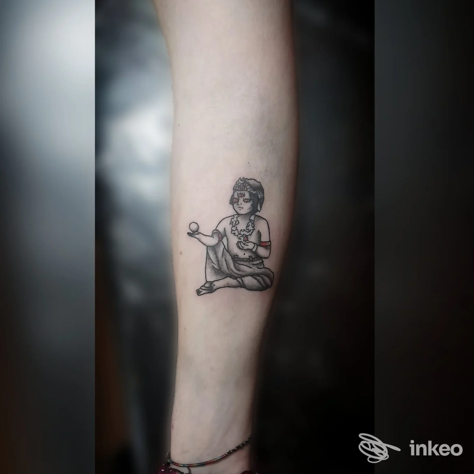 Tattoo su avambraccio raffigurante una persona seduta che tiene un palloncino, disegno in linea nera su pelle chiara.