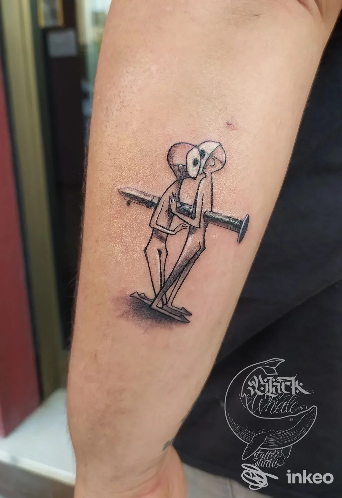 Braccio con tatuaggio raffigurante una figura stilizzata che regge un chiodo, realizzato presso Black Whale Tattoo ad Alba Adriatica.