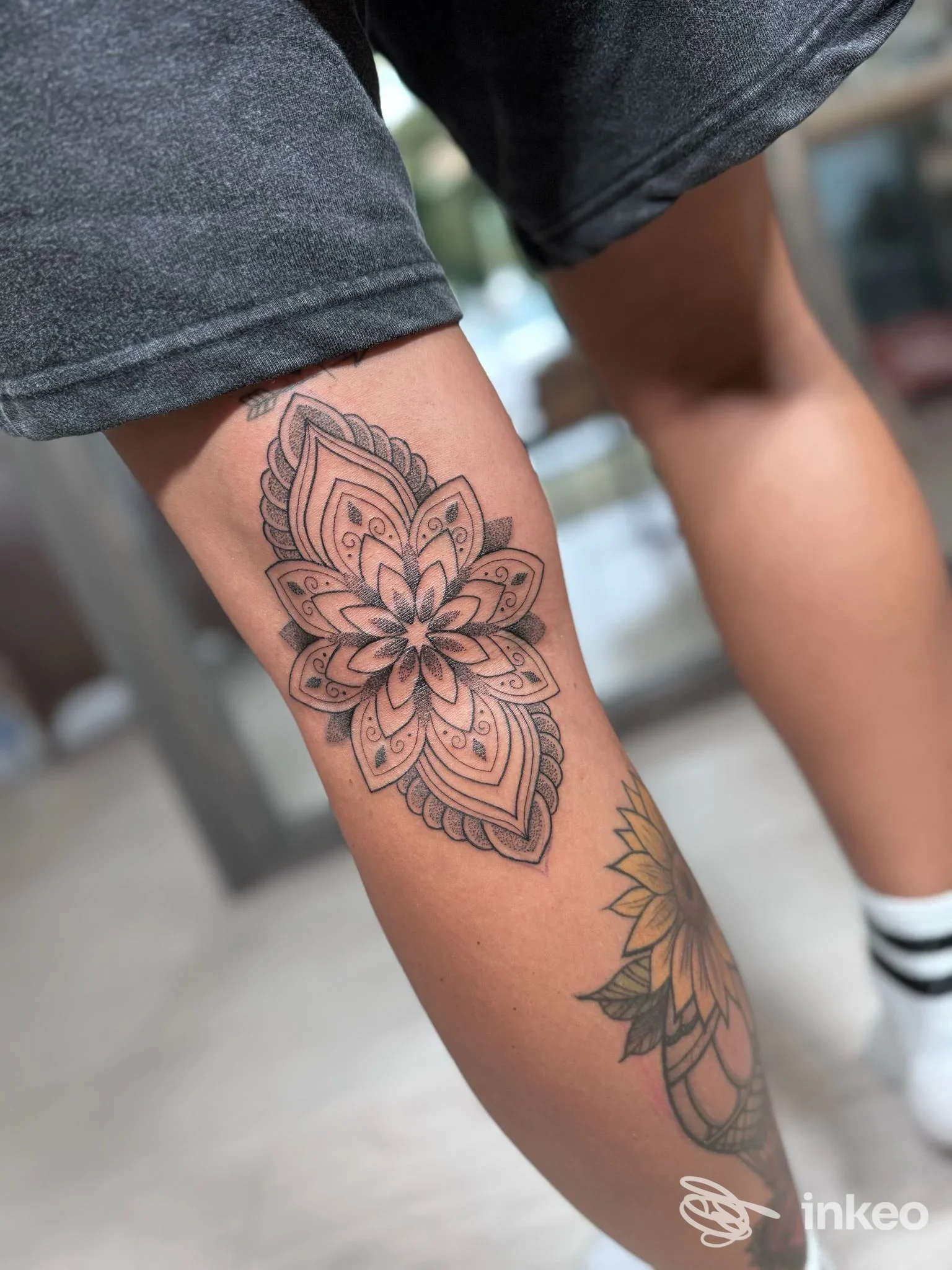 Tattoo sul polpaccio di una persona: disegno floreale in stile mandala realizzato sullo skincare, visibile vicino alla gamba, con colori neri e sfumature.