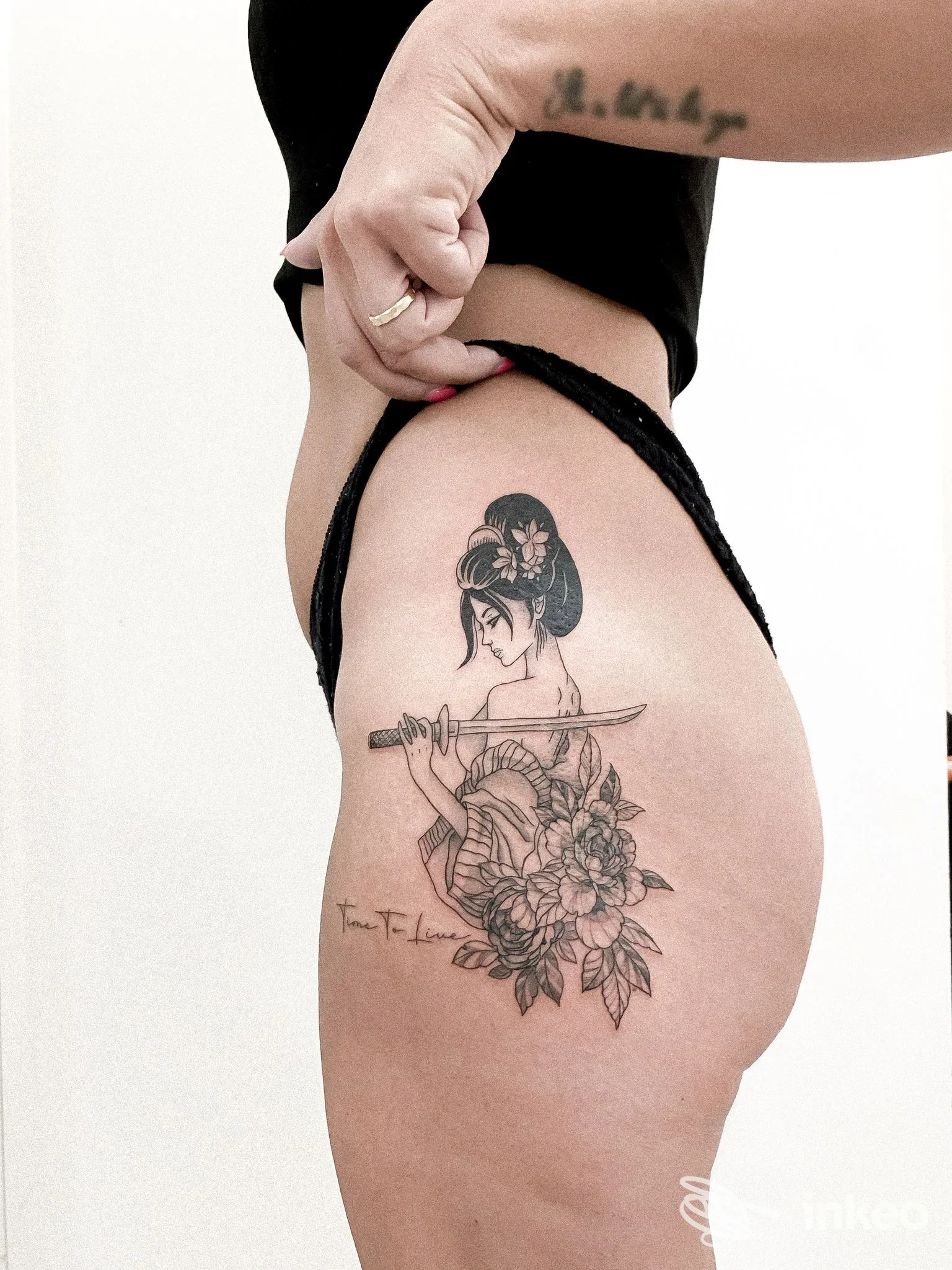 Tattoo visibile sulla coscia di una persona, raffigurante una figura femminile con spada e fiori, realizzata da Ilda Mema Dermolab a Lanciano.