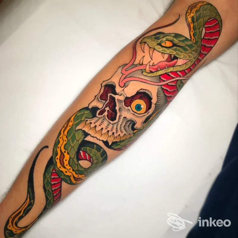 Tattoo colorato sull'avambraccio raffigurante un teschio avvolto da una serpente verde e gialla, realizzato da Di Brigida Tattoo Studio a Pescara.