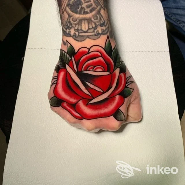Tatuaggio reale a rosa rossa sul dorso della mano, colori vividi e linee nette; si intravede parte di un altro tatuaggio in alto sull’avambraccio. realizzato dallo studio 16th Ball a Lanciano.