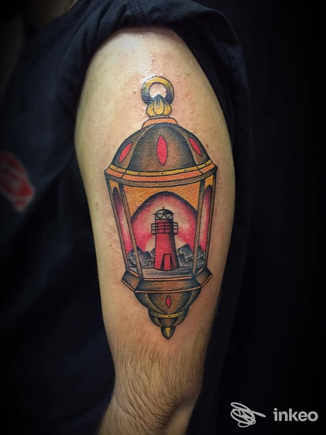 Tattoo a lampione luminoso sulla parte superiore del braccio, colori vividi gialli, rossi e neri, realizzato sulla pelle in stile tradizionale.