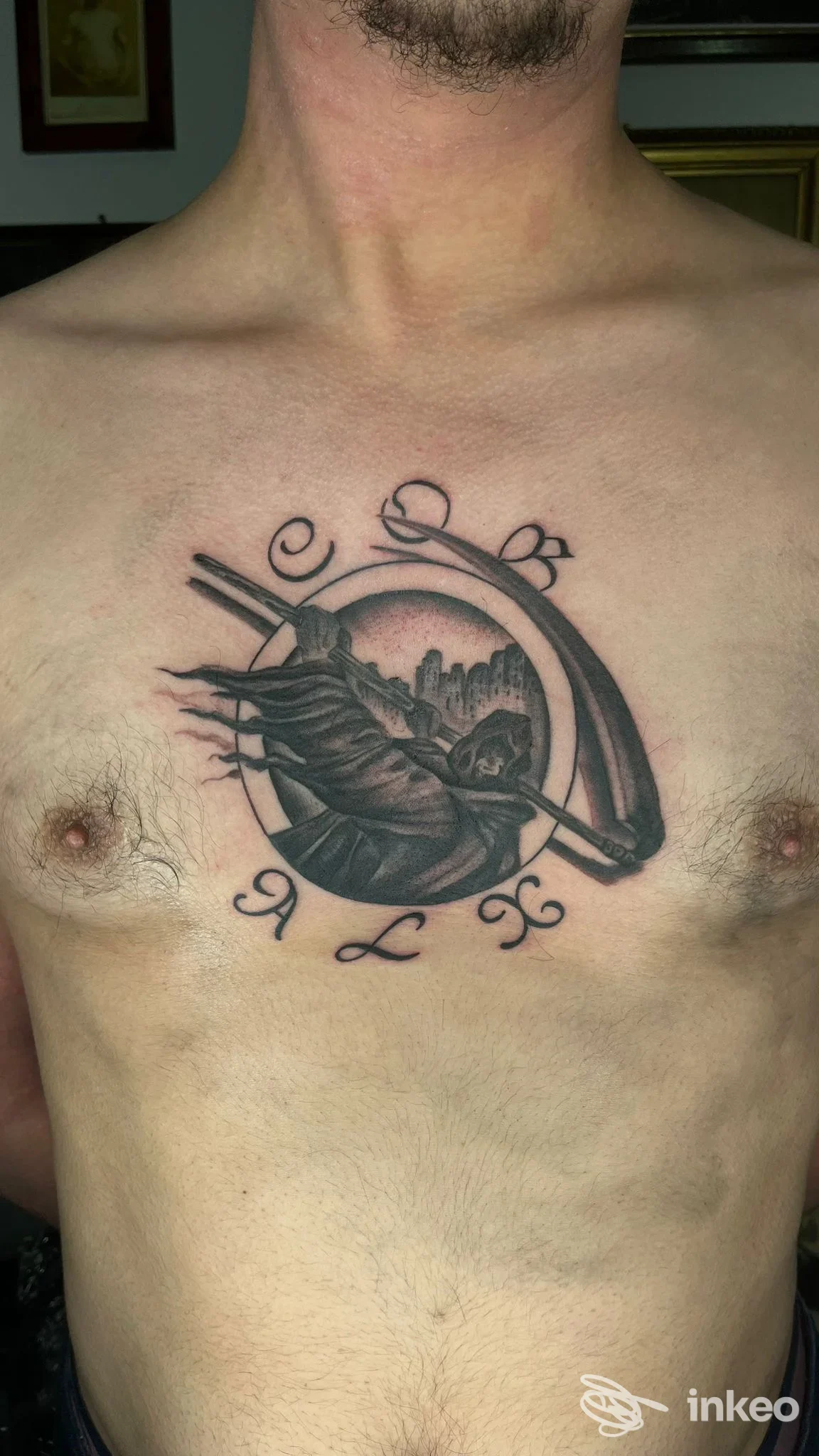 Uomo ritratto dal torace: tatuaggio incisivo a tema circolare con figura stilizzata, linee nere su pelle chiara, senza elementi promozionali o overlay social.