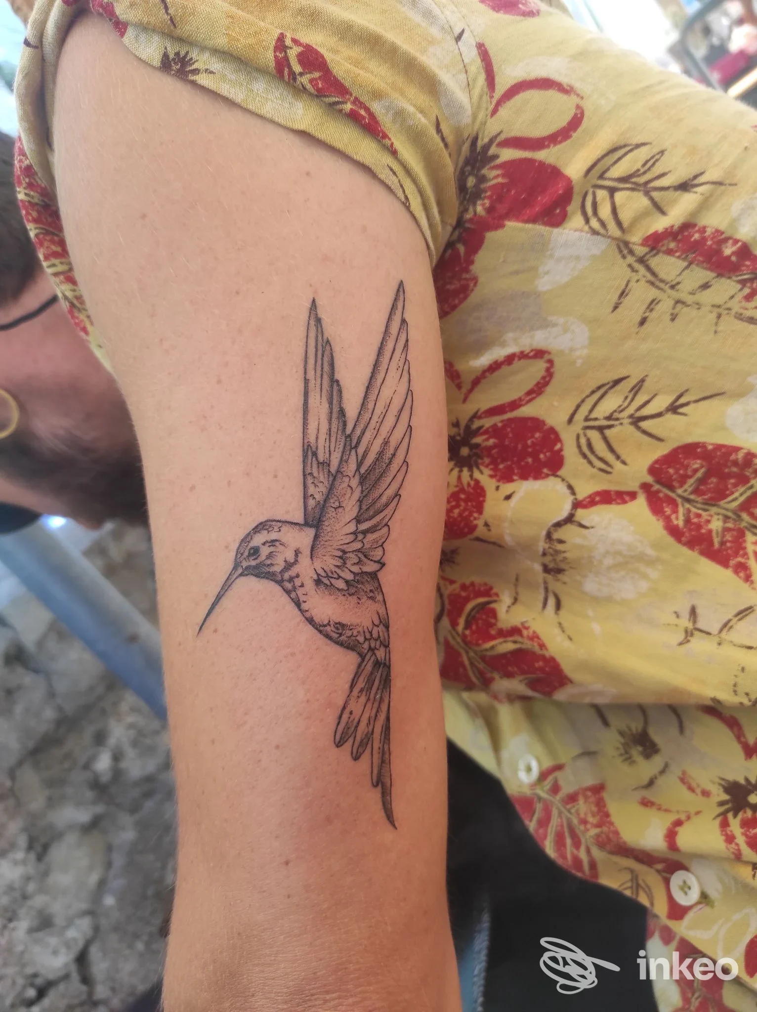 Tattoo in stile linework di un colibrì su braccio, eseguito sulla pelle, visibile la parte della manica della maglia gialla. Studio Skull Corner Tattoo Studio, Vasto.