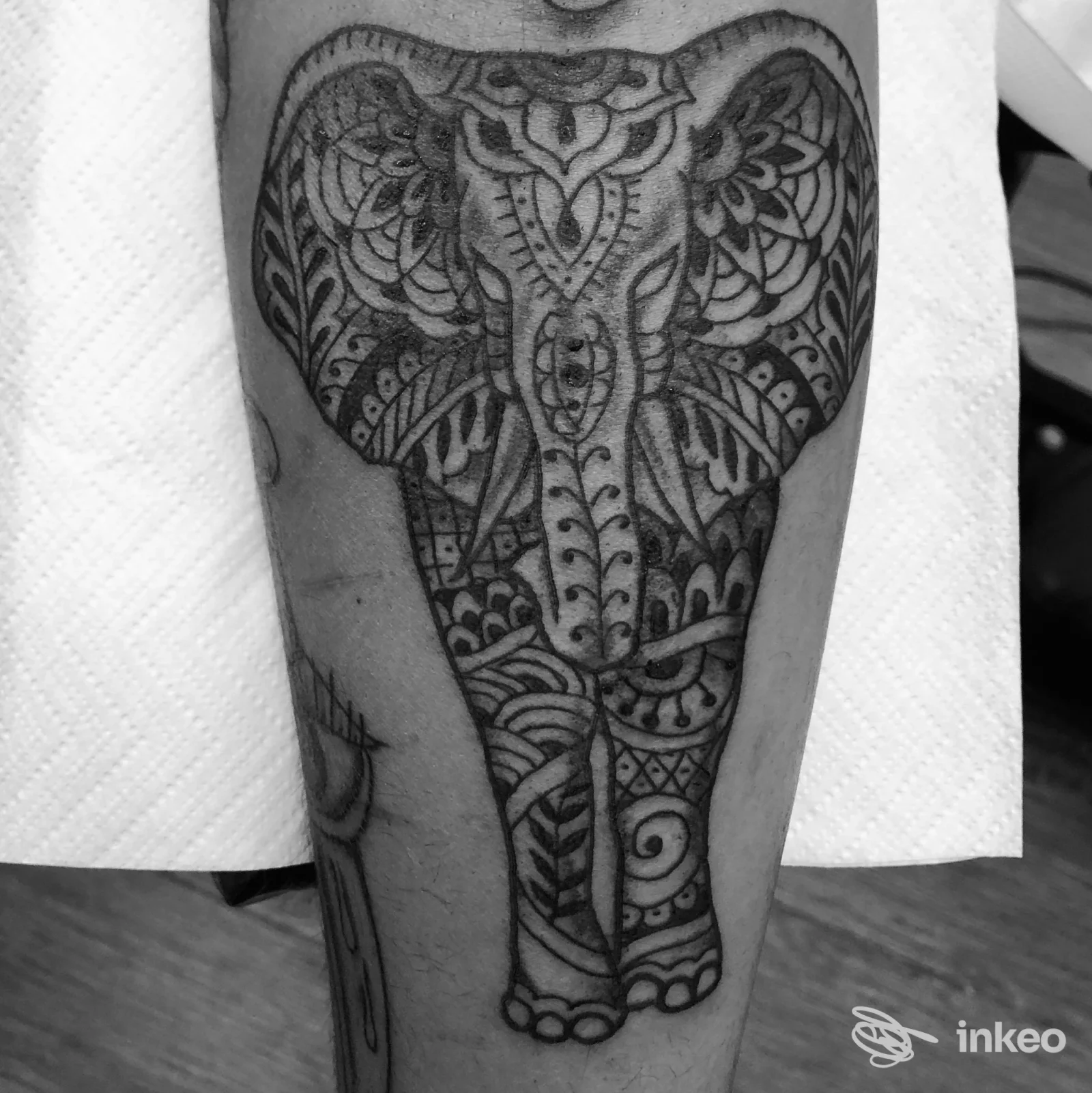 Una foto in bianco e nero mostra un tatuaggio ornato sull’avambraccio, con motivi intricati che formano un disegno coerente sull’intera superficie della pelle.