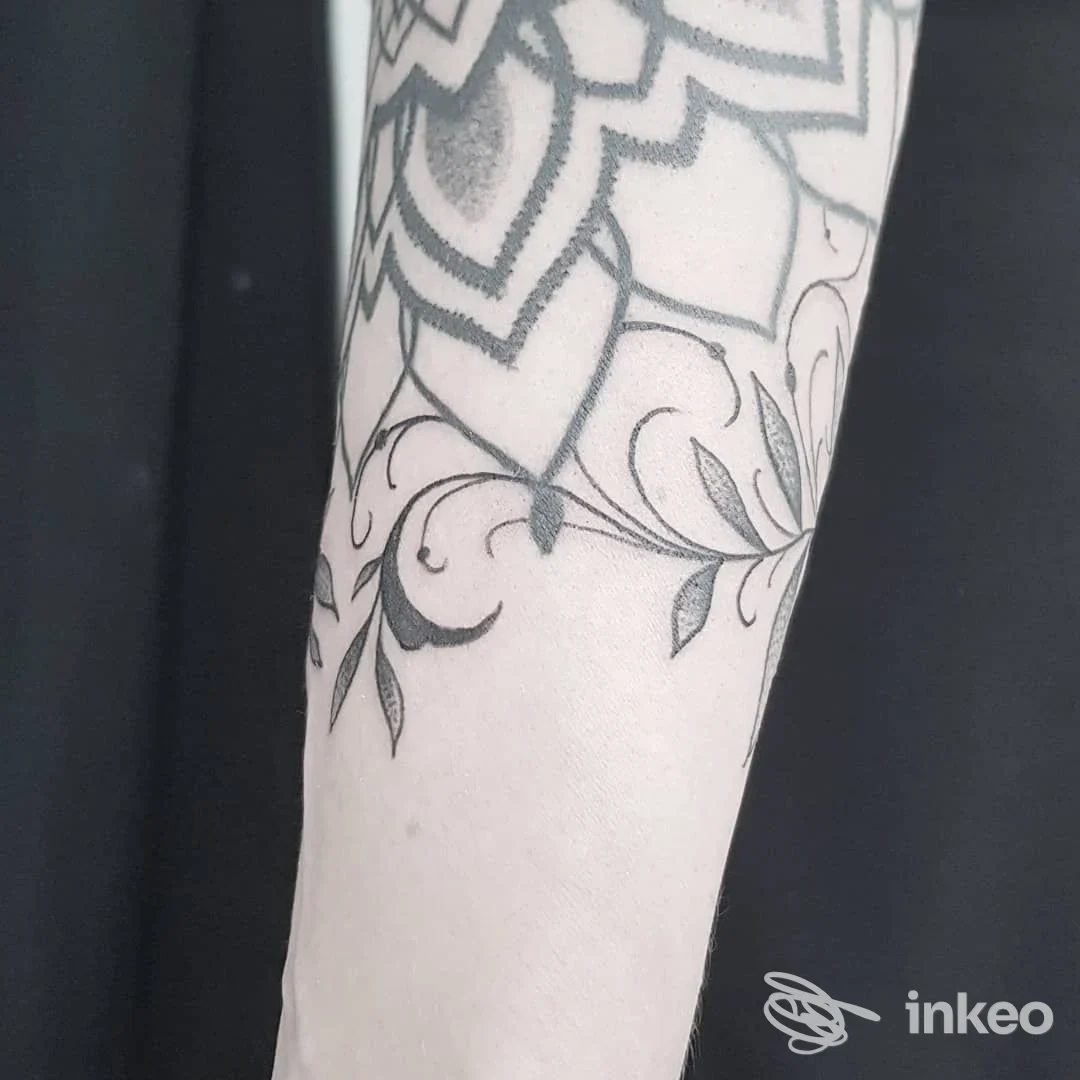 Parte di avambraccio con disegno di fiori stilizzati in prevalenza in nero, con linee sottili e ombreggiature leggere.