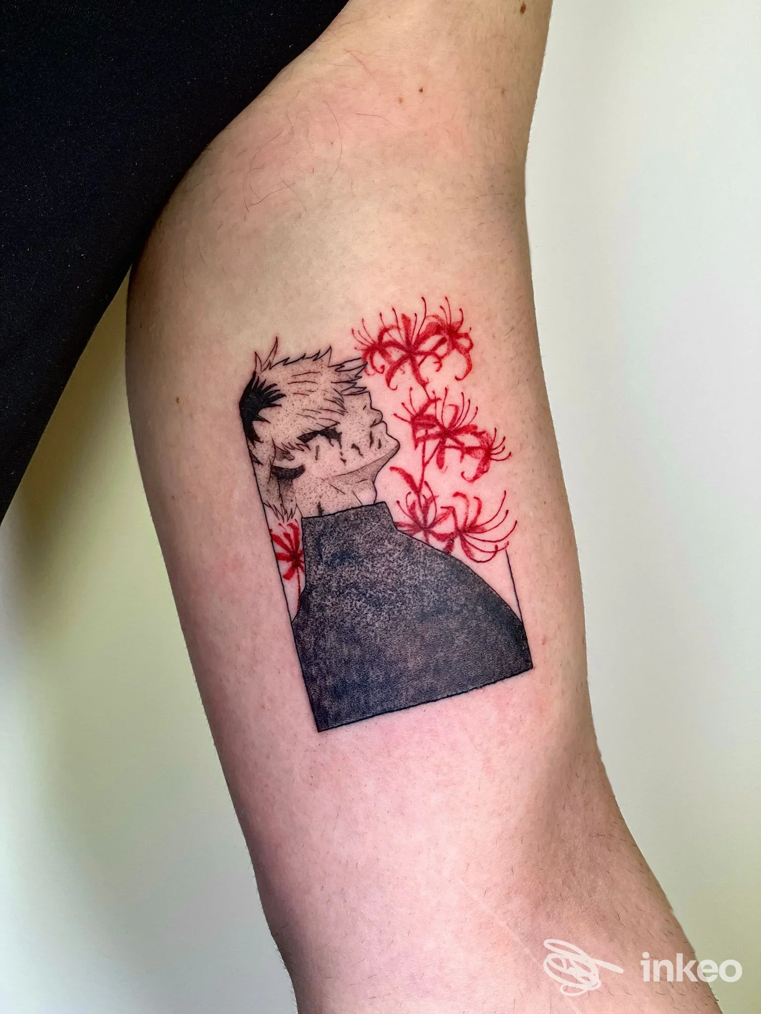 Tattoo sul braccio visibile: disegno stilizzato in bianco e nero con fiori rossi che esce dalla silhouette del braccio; realizzato presso Momiji Tattoo Studio a Pescara.