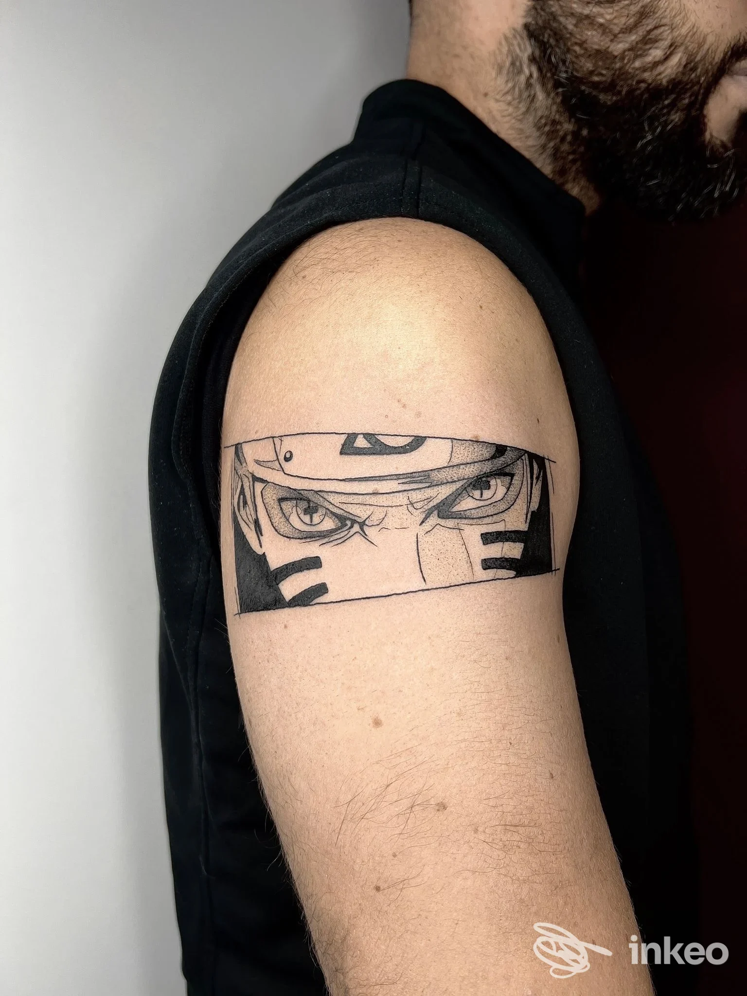 Dettaglio di un tatuaggio sul braccio di un uomo, raffigurante occhi e linee nere; studio Momiji Tattoo Studio a Pescara.