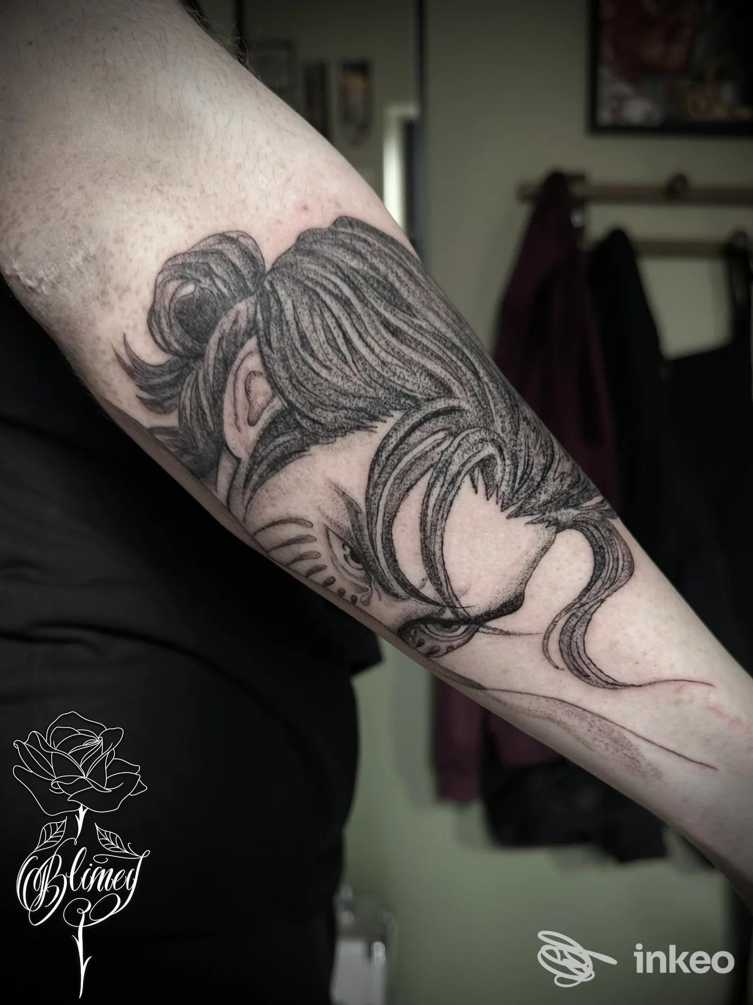 Braccio sinistro con tatuaggio realistico di una figura femminile dai capelli lunghi, realizzato in stile grafico; firma dello studio Blimey Tattoo in Avezzano visibile nell’angolo.