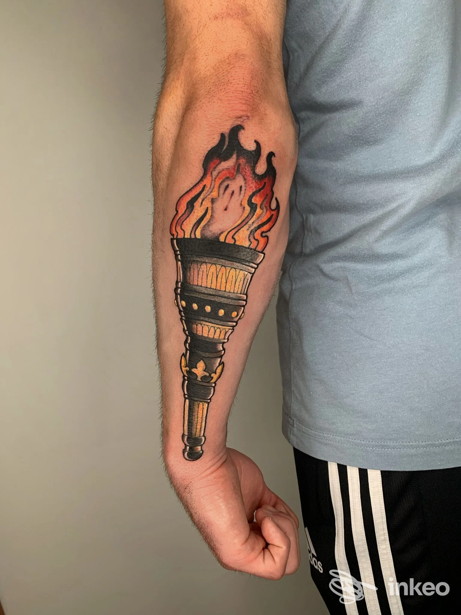 Tatuaggio di una torcia in stile tradizionale con fiamme arancioni e rosse sull’avambraccio, realizzato da Julia Porter Tattoo, Montesilvano.