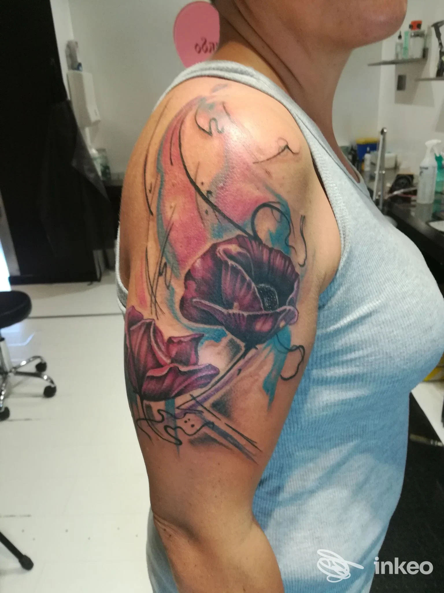 Tatuaggio colorato di fiori su braccio di una persona, realizzato nello studio Tattoo Storm a Vasto, visibile in un ambiente interno.