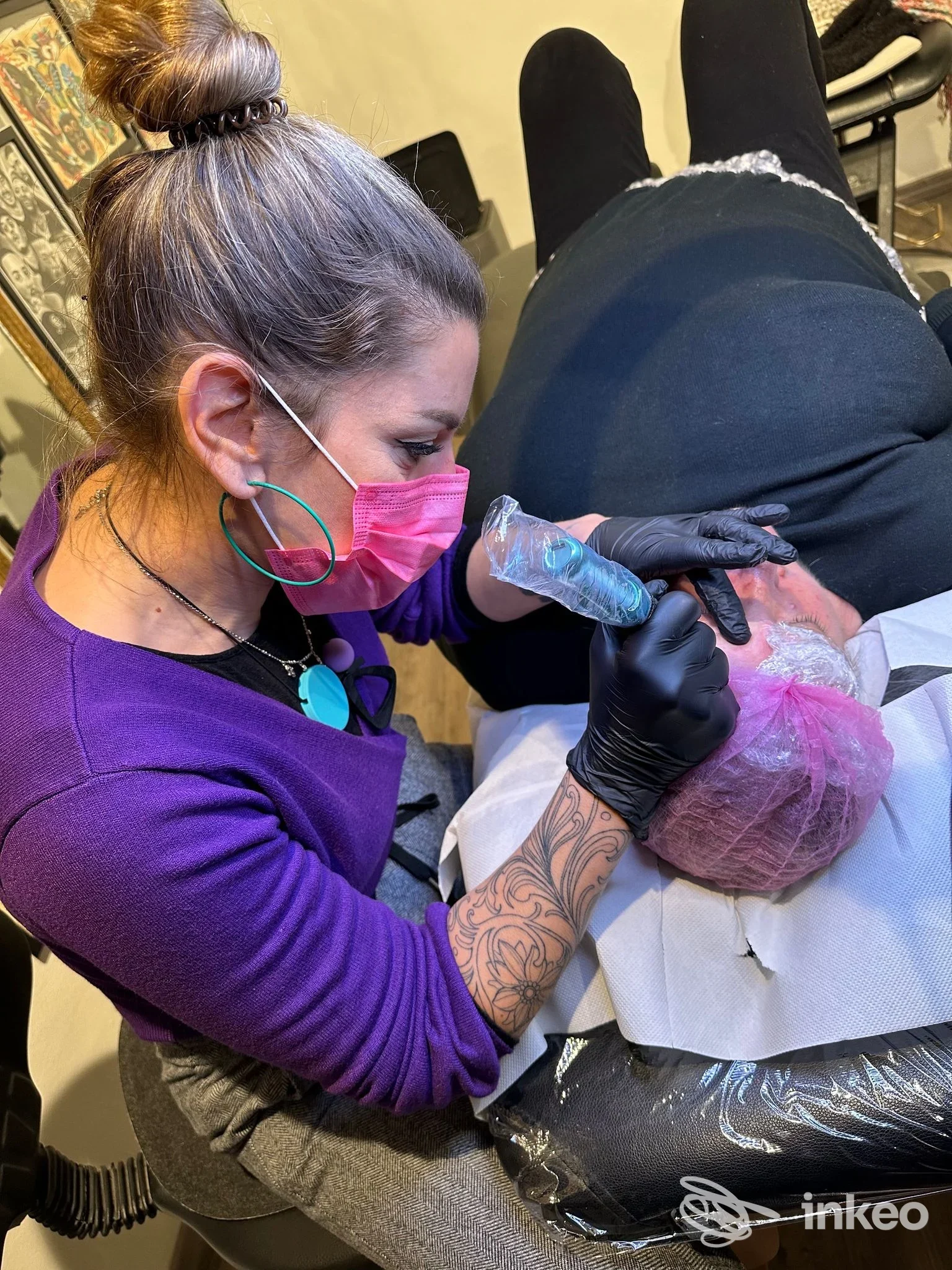 Operatrice con mascherina rosa e guanti esegue trucco permanente sull'arco sopraccigliare di un cliente, in uno studio Sabri Permanent Makeup a Pineto.