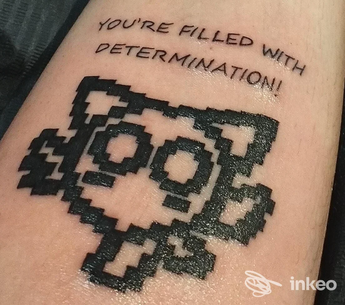 Tattoo sull'avambraccio raffigurante una grafica pixel art e un testo: "YOU'RE FILLED WITH DETERMINATION!" realizzato da Underground Clinic, Avezzano.