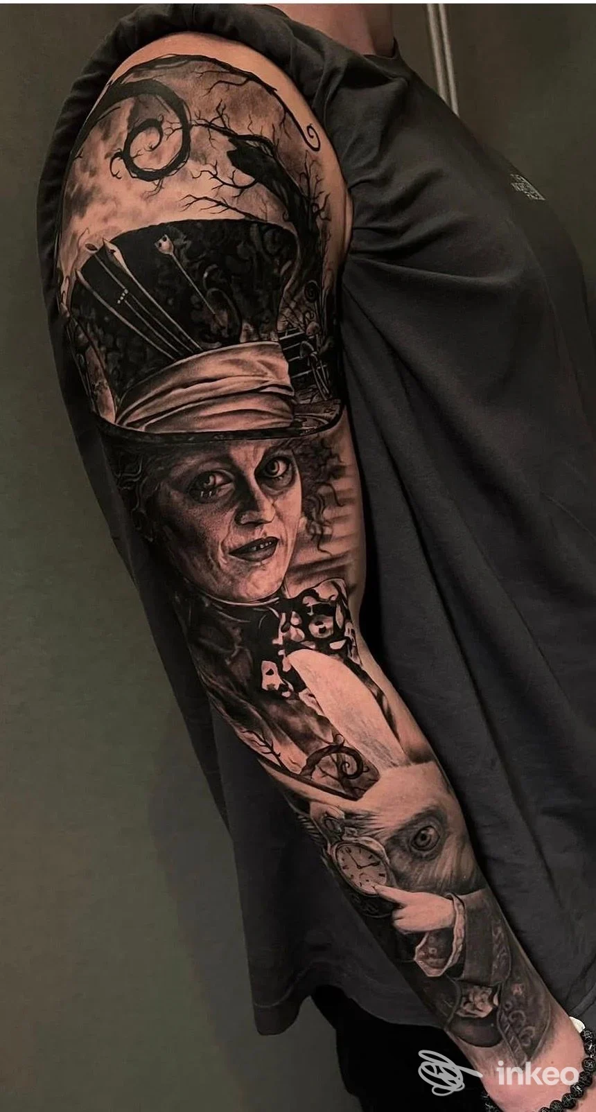 Tatuaggio a maniche completa su braccio, ritraente una figura con cappello e trucco teatrale, stile scuro e dettagli realistici.