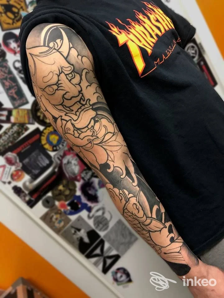 Tattoo a maniche intera con disegno a linee nere su pelle, braccio sinistro, rappresentazione di fiori e figure astratte su sfondo grigio. Studio Italian Style Tattoo, Montesilvano.