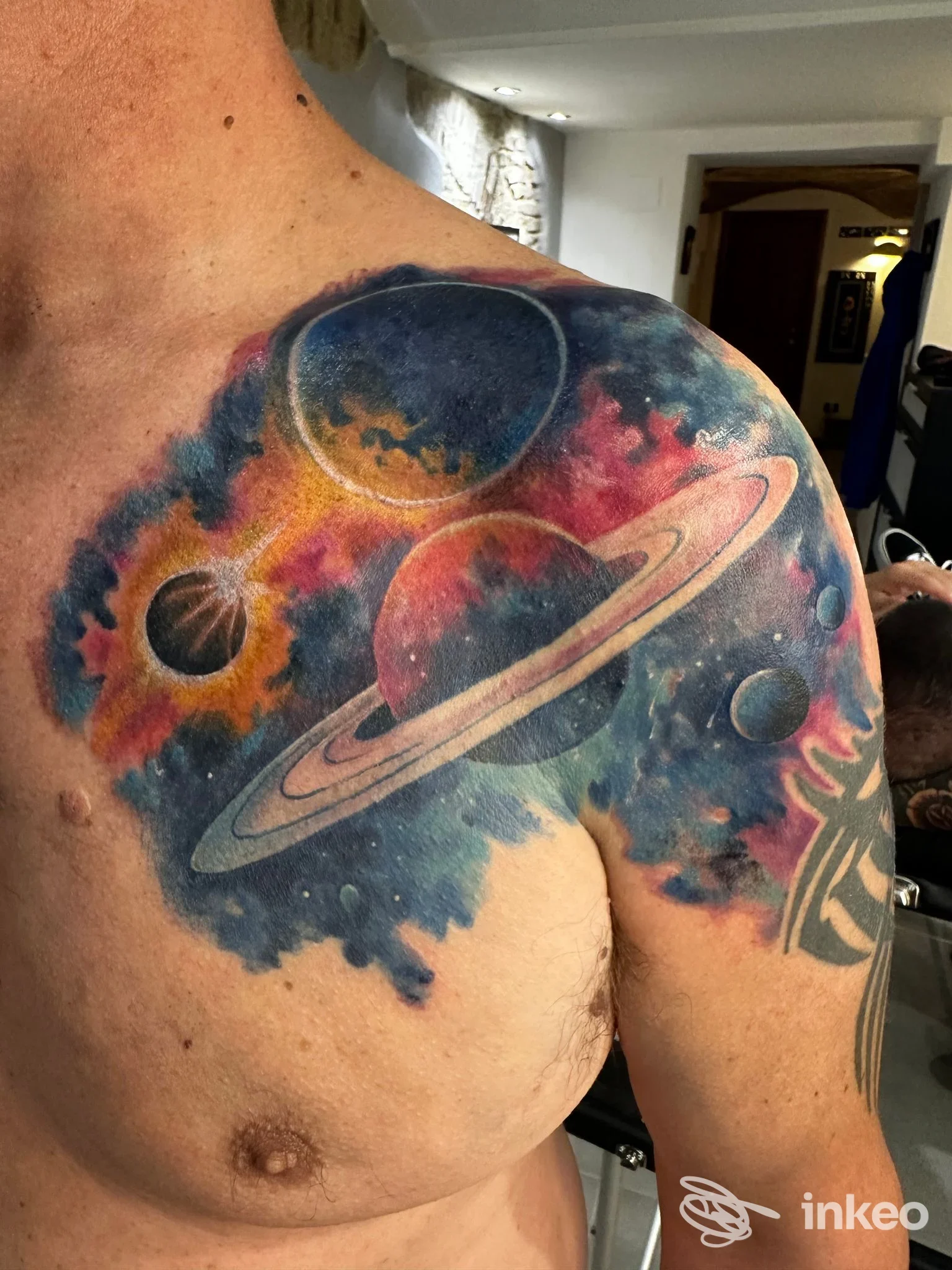 Tattoo realistico su spalla e petto raffigurante una scena galattica con pianeti colorati e Saturno, realizzato nello studio Underskin Tattoo a Lanciano.
