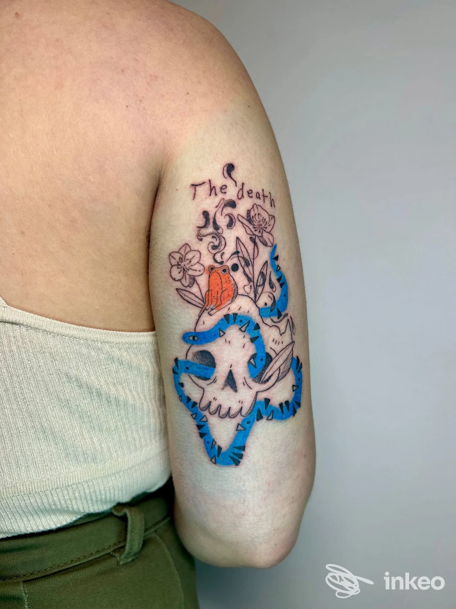 Tattoo colorato sul braccio di una persona, design disegnato e tratto con linee nere su sfondo chiaro, senza viso visibile.