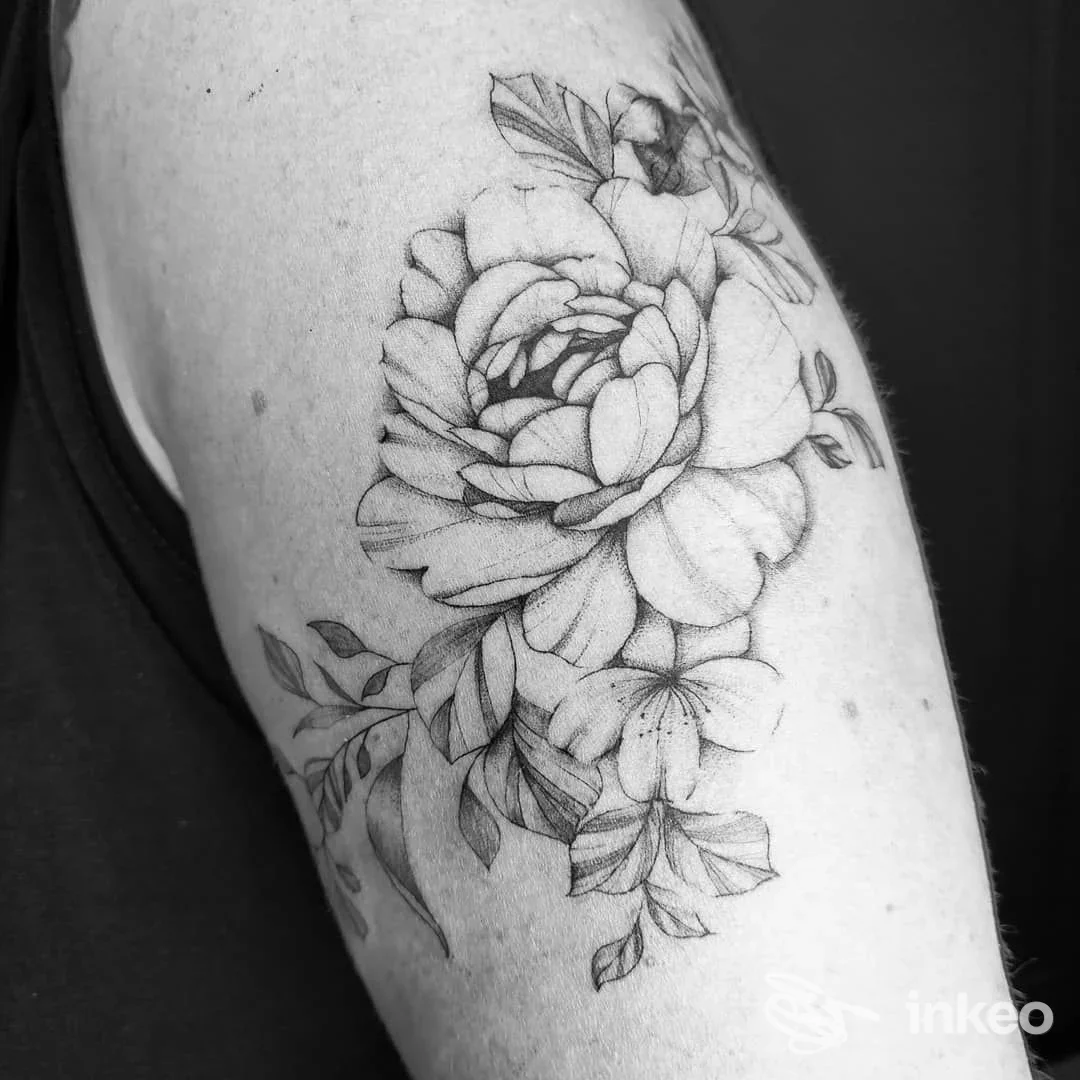 Tattoo floreale su braccio, grande fiore al centro con foglie, realizzato in bianco e nero su pelle nuda.