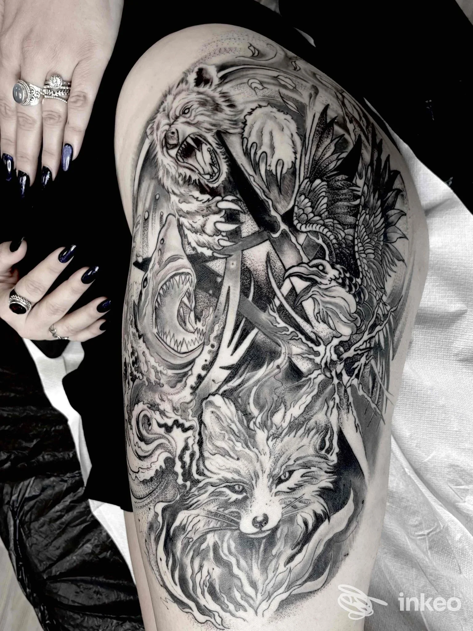 Tattoo a tema animale su gamba: lupo, orso e volo di uccelli in stile realistico, in bianco e nero, su pelle nuda.