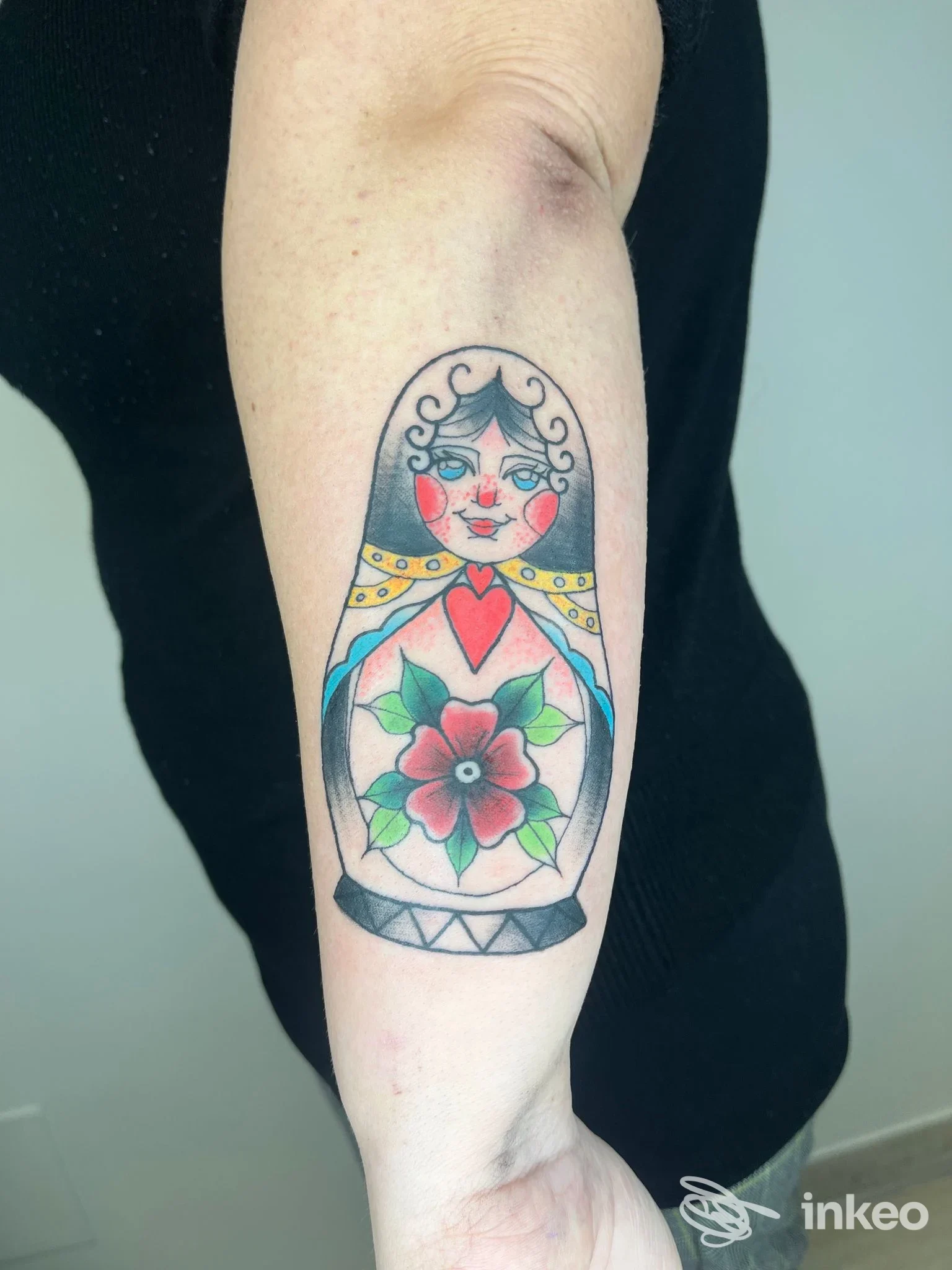 Tatuaggio su avambraccio raffigurante una matrioska con fiori colorati e volto stilizzato, eseguito nello studio The Greenwood Tattoo a Pescara.