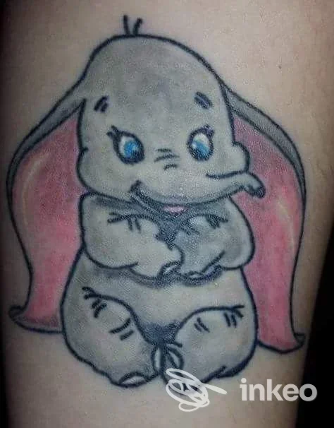 Piccolo tatuaggio su avambraccio raffigurante un elefantino cartoonesco con orecchie rosa, colori pastello, stile kawaii.