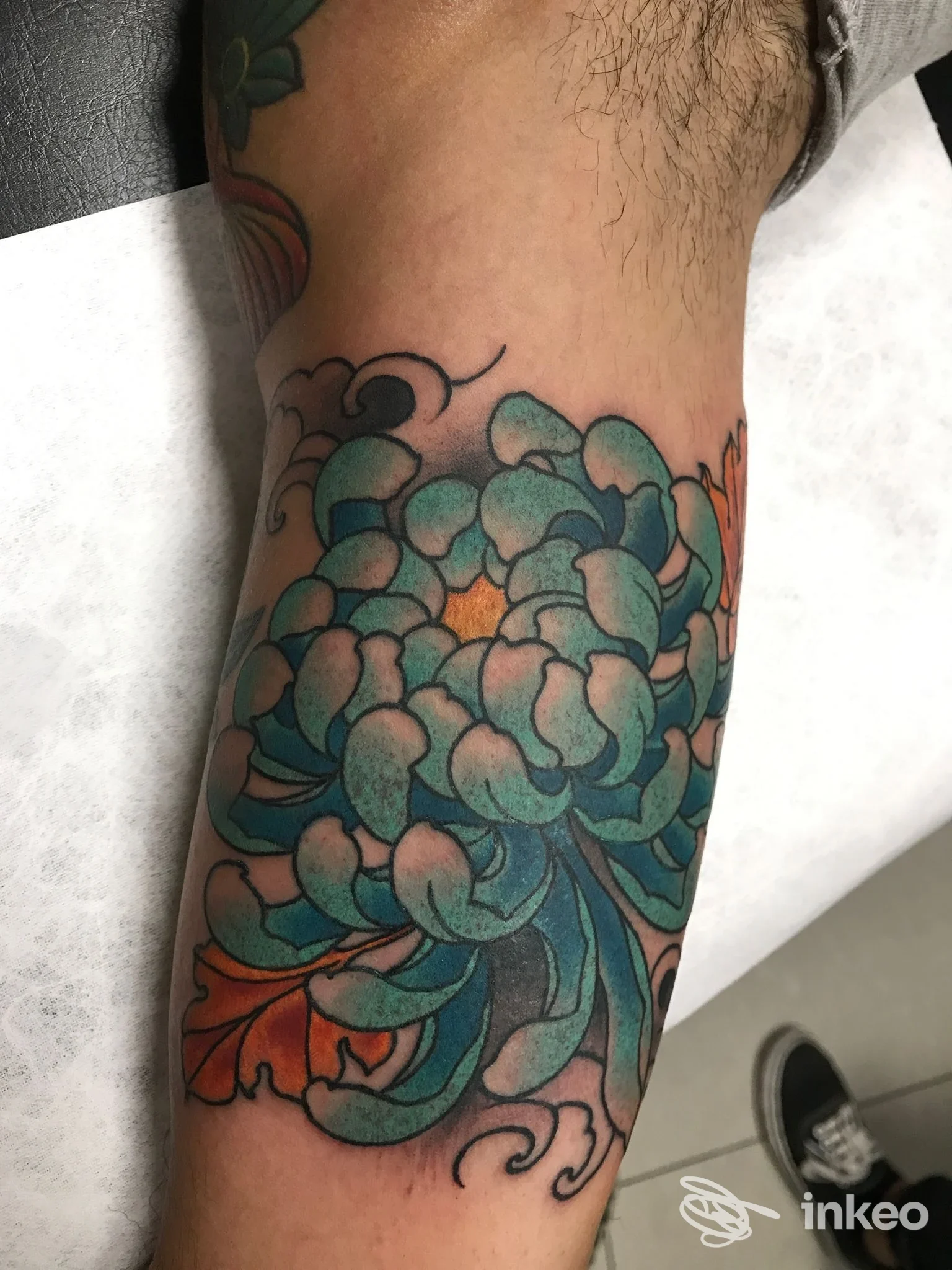Tatuaggio colorato su avambraccio, motivo floreale con tonalità azzurre e verdi realizzato nello studio Ink Master Tattoo a Montesilvano.