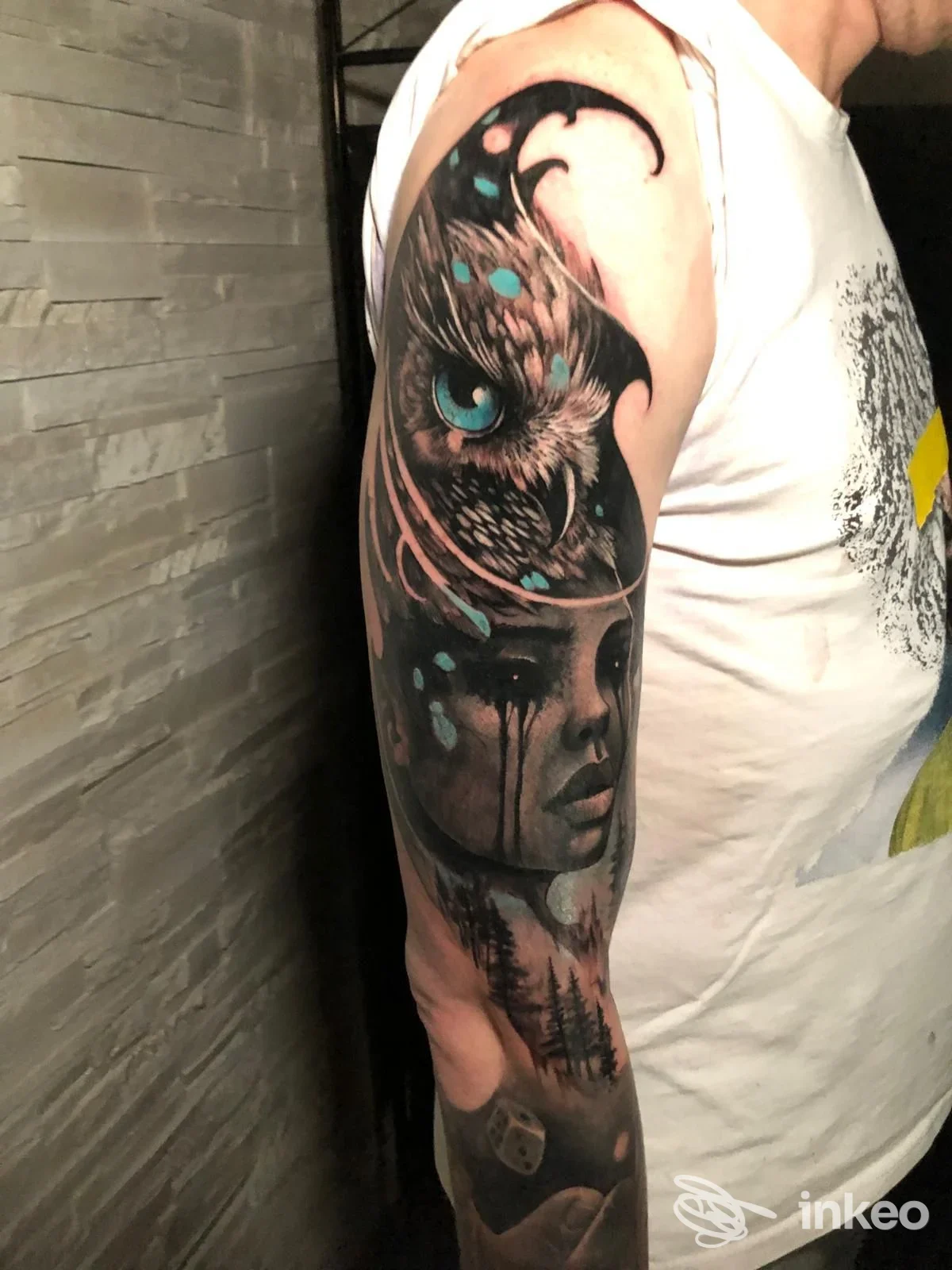 Tattoo a braccio sinistro raffigurante una figura femminile con un circa animale con occhi azzurri, tonalità scure e sgargianti schizzi azzurri; lavoro di Incisotattooart&co a Pescara.