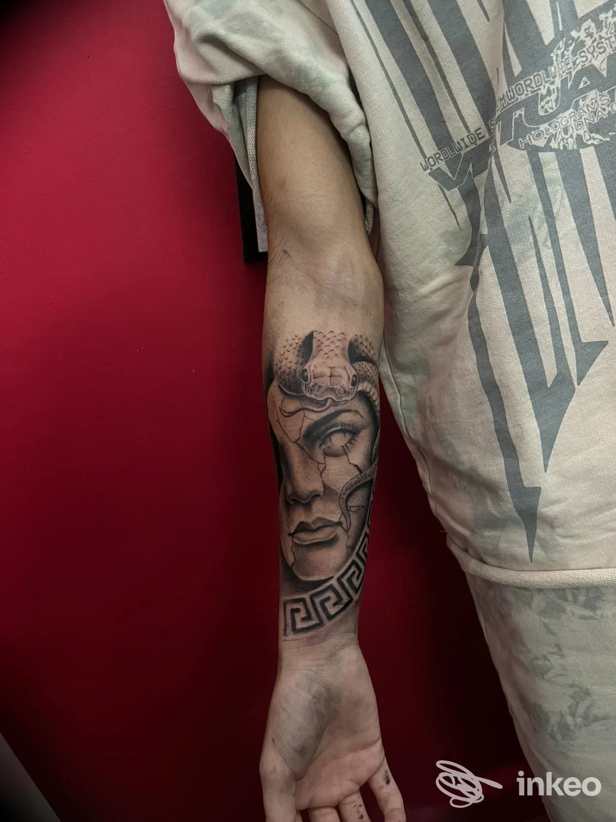Dettaglio di tatuaggio sul braccio: volto stilizzato e motivi geometrici lungo l'avambraccio, realizzato su pelle reale.